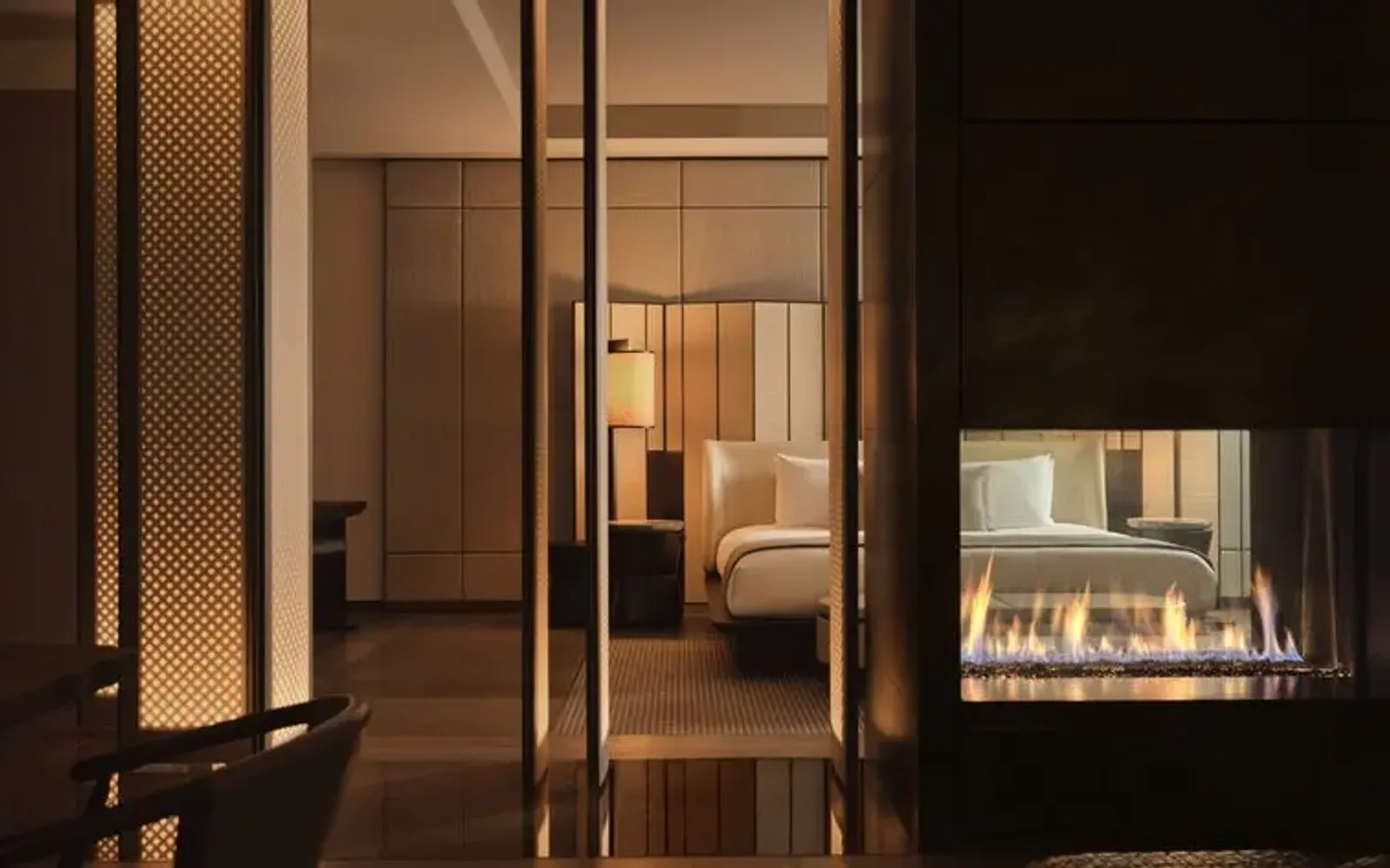 Aman New York entrance with illuminated glass doors opening to a warm, minimalist interior at dusk.