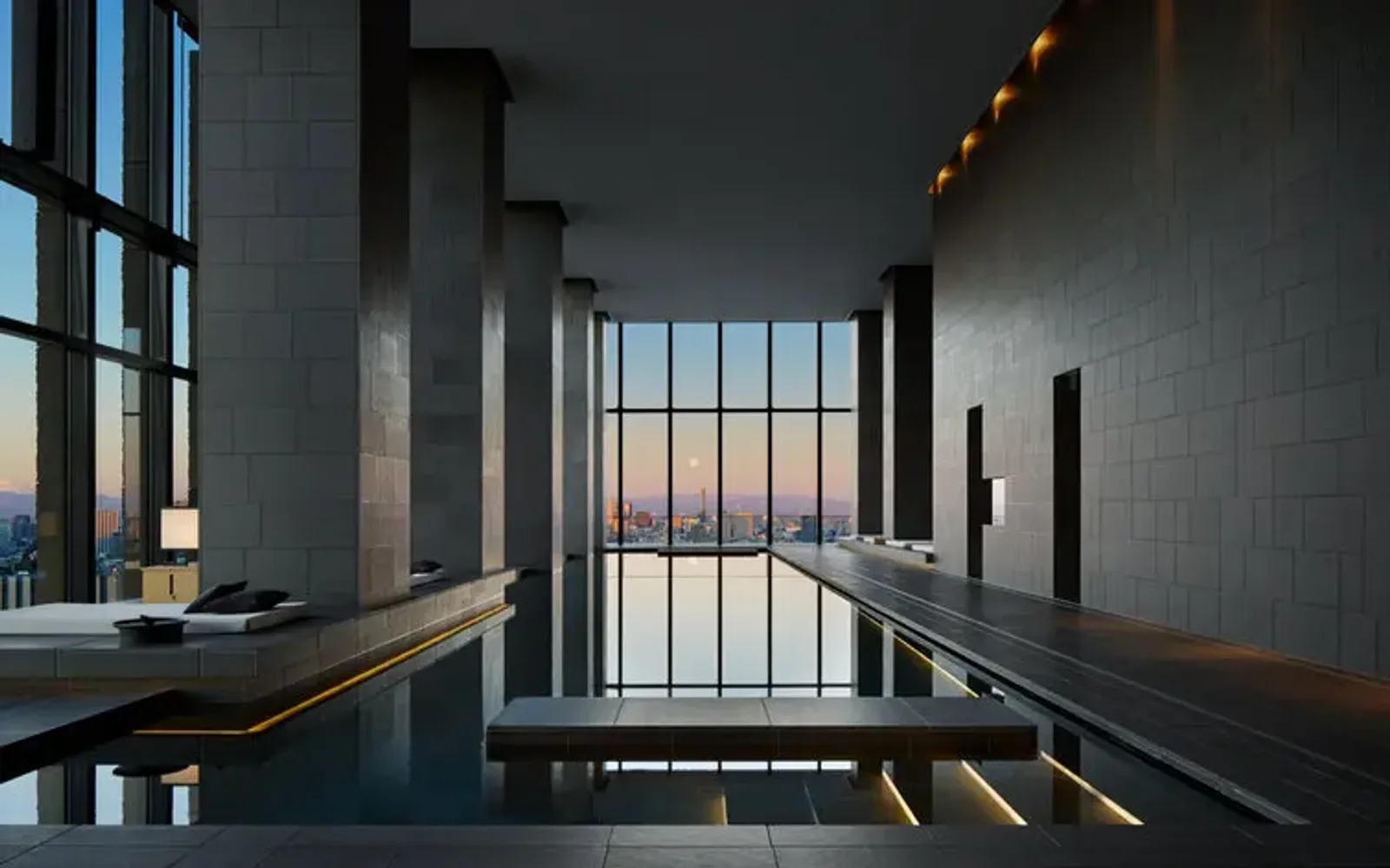 Aman Tokyo wellness spa pool overlooking the city skyline at dusk.