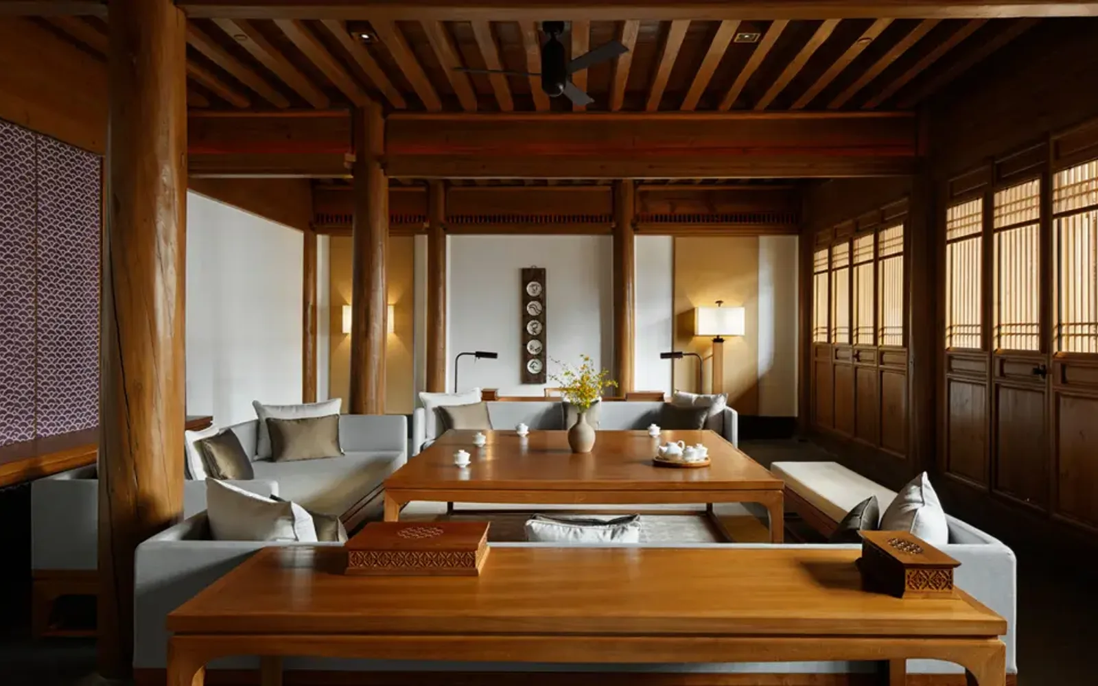 Amandayan villa living area with wooden furnishings, shoji screens, and natural light from floor-to-ceiling windows.