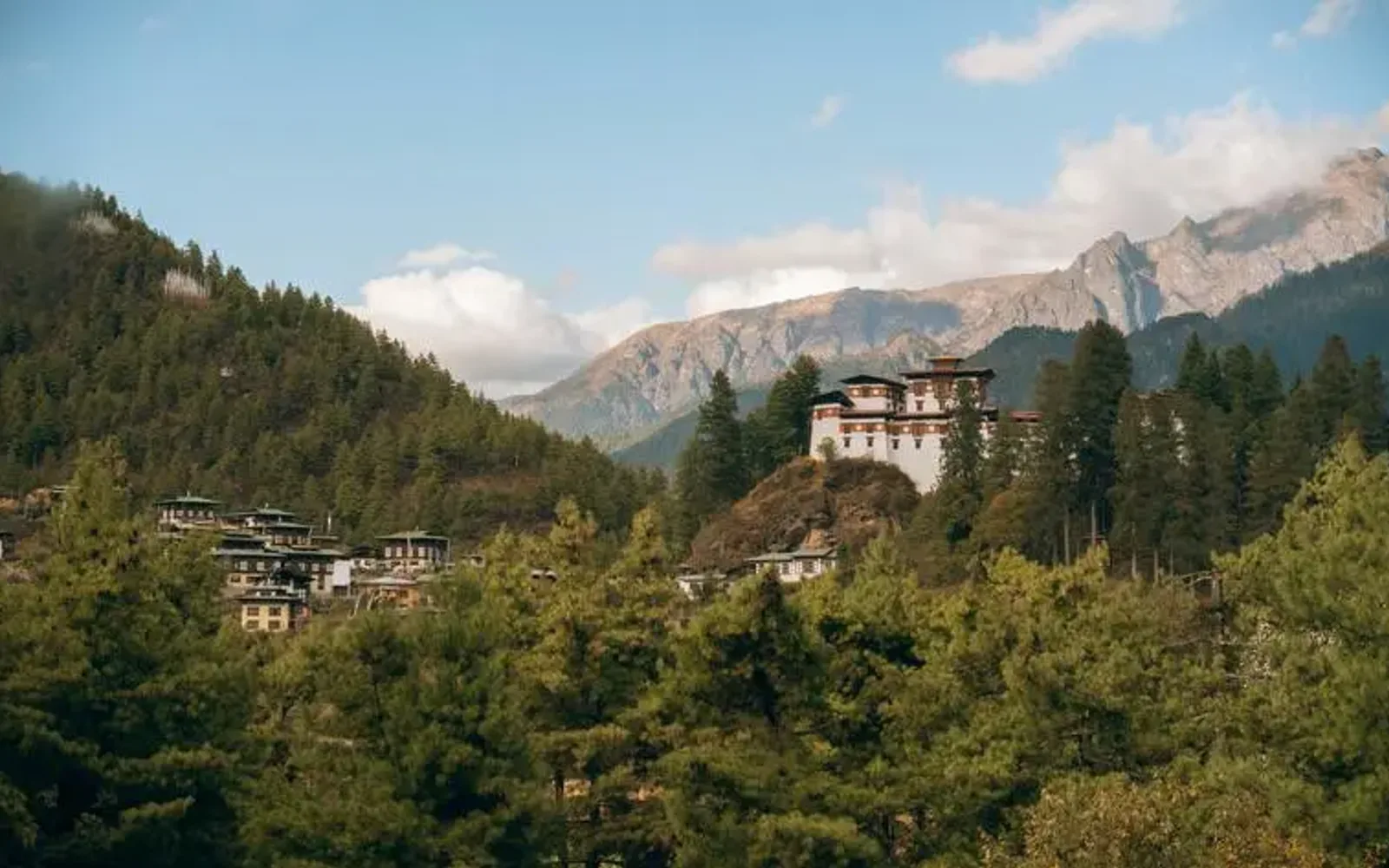 Amankora perched on a forested hillside in Paro valley, Bhutan, with mountains beyond.