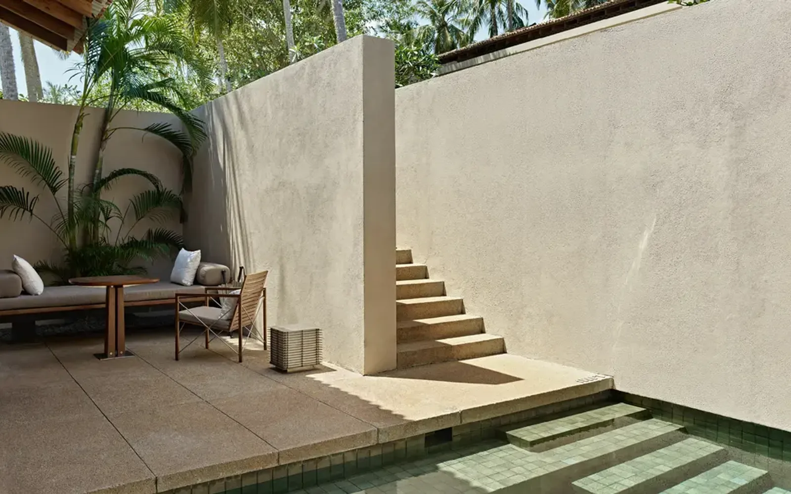 Courtyard at Amanwella with stone steps, seated figure, and planted palms.