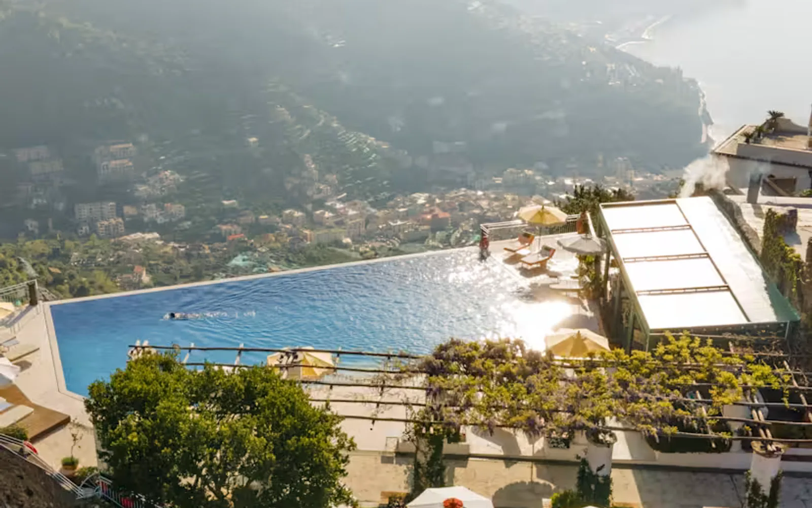 Six parasols offer shade to sun-loungers on a deck behind the pool which drops off into sublime coast views, seen from above.