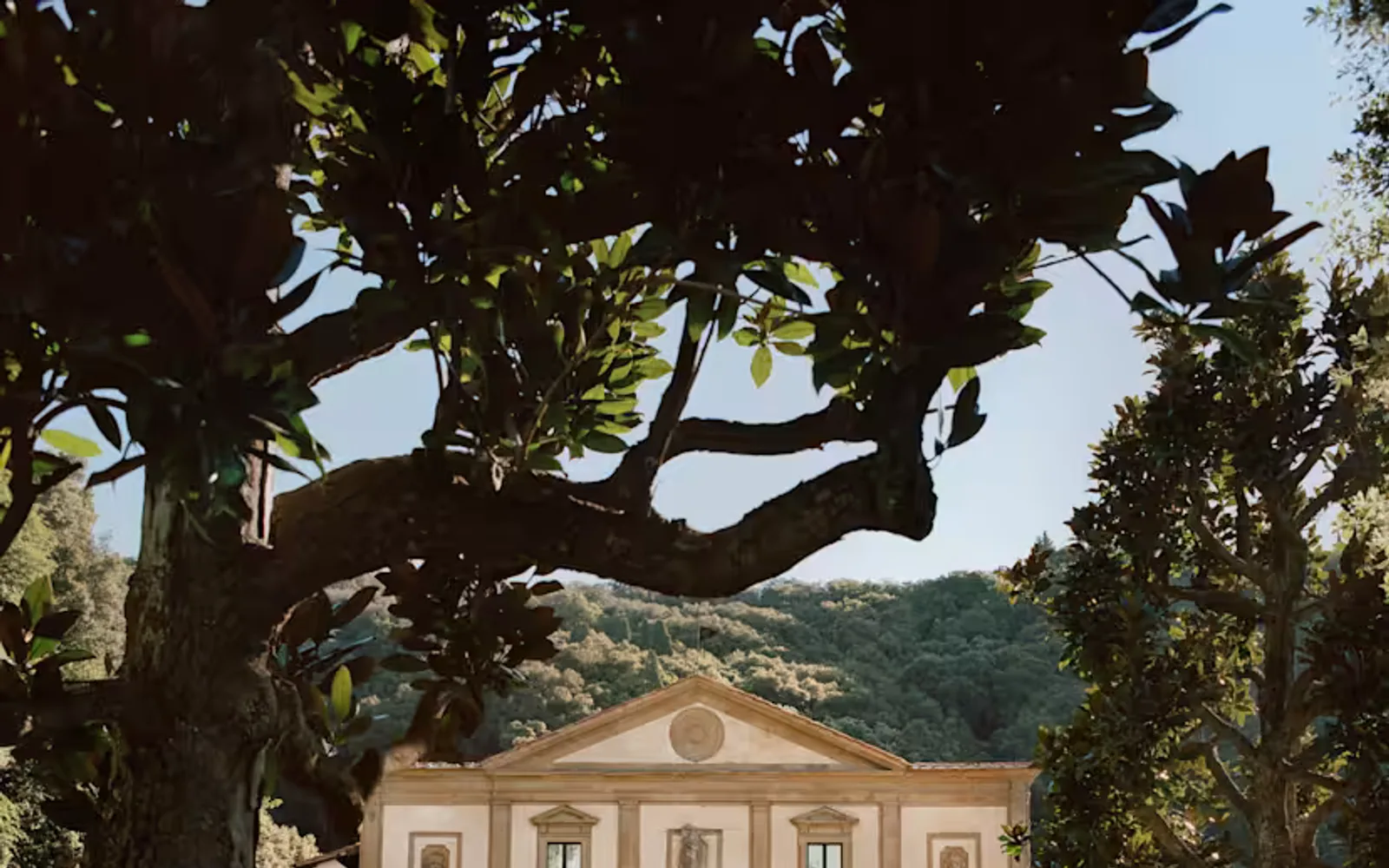 The Michelangelo-designed facade stands with palest pink walls amid a sea of green as lush hills climb up behind the gardens