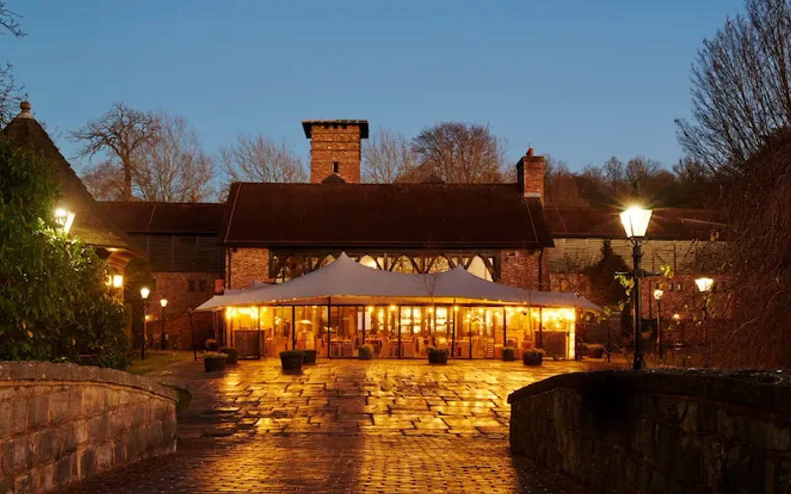 Coworth Park, The Barn, exterior at night with golden light