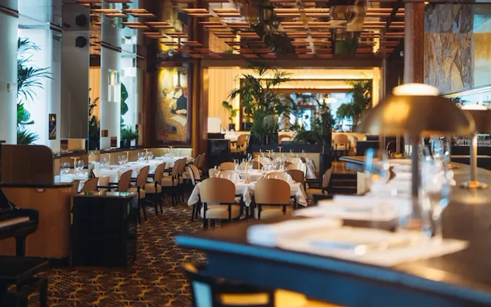 Overview of Le Relais Plaza's dining room lower deck, with the bar at the forefront,at Hotel Plaza Athénée, Paris