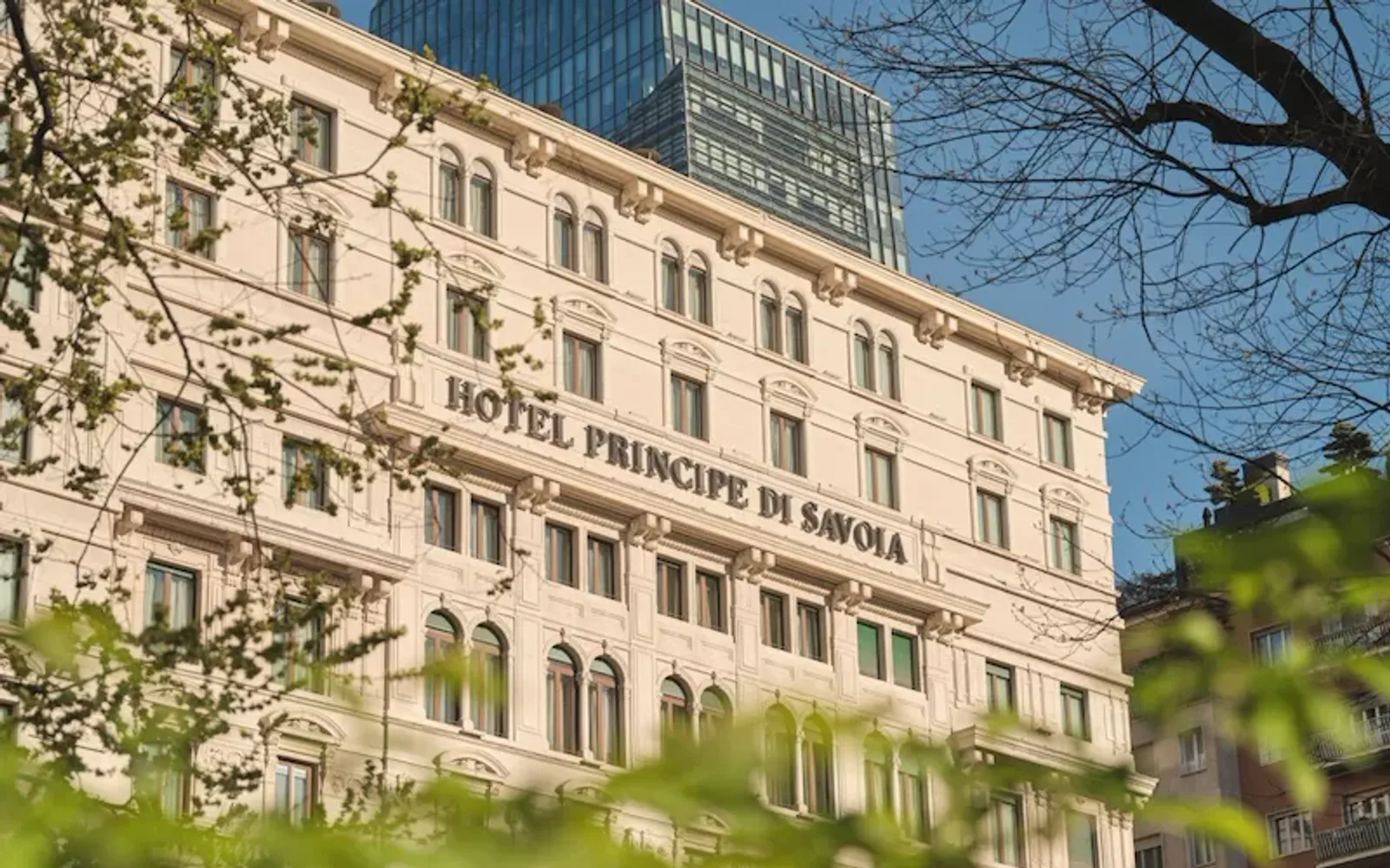 Our Hotel neoclassical facade, with green leaves in the foreground, blurred.