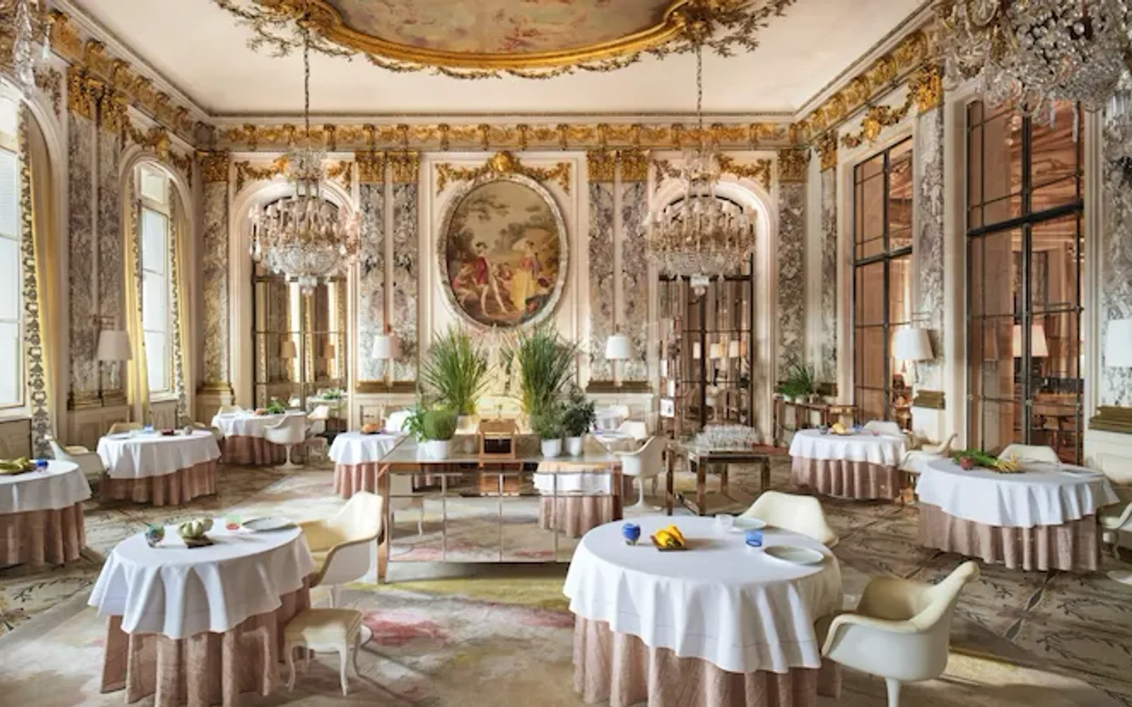 Large view of Le Restaurant le Meurice Alain Ducasse with the furnitures, the chandeliers, the plants and the food on the tables, at Le Meurice, Paris