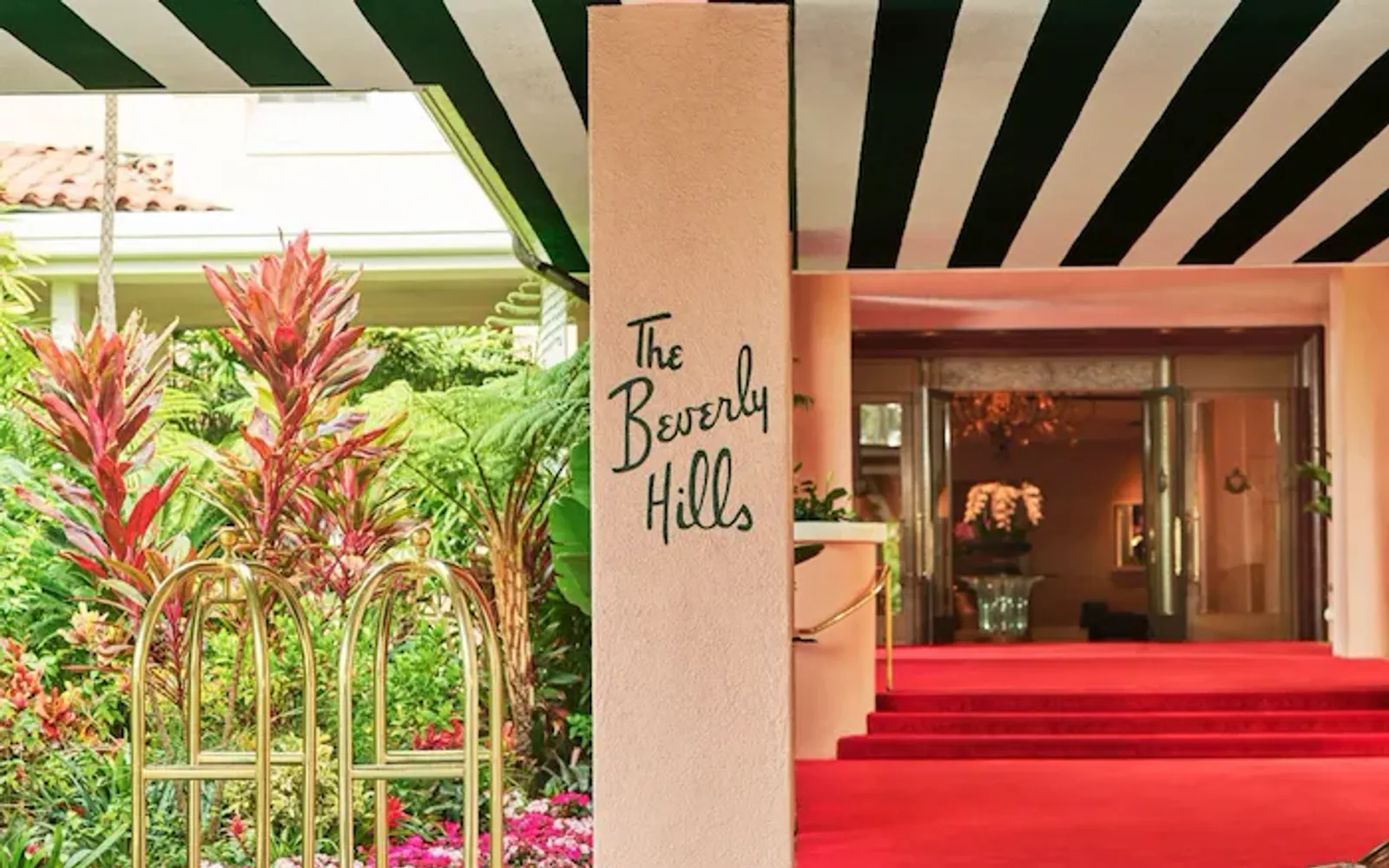 The Beverly Hills Hotel red carpet entrance with car and bellman carts.