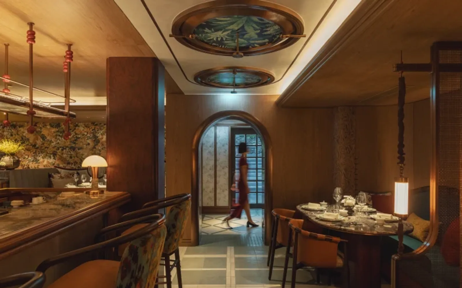 the restaurant interior with warm lighting, marble bar, and a woman walk pass the door