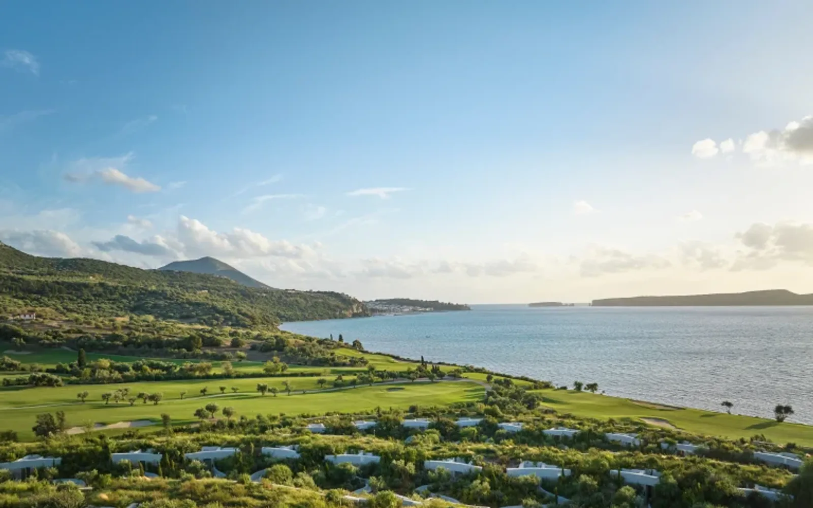 A view of earth-sheltered villas at Mandarin Oriental, Costa Navarino, featuring planted green roofs that seamlessly blend into the natural hillside landscape.