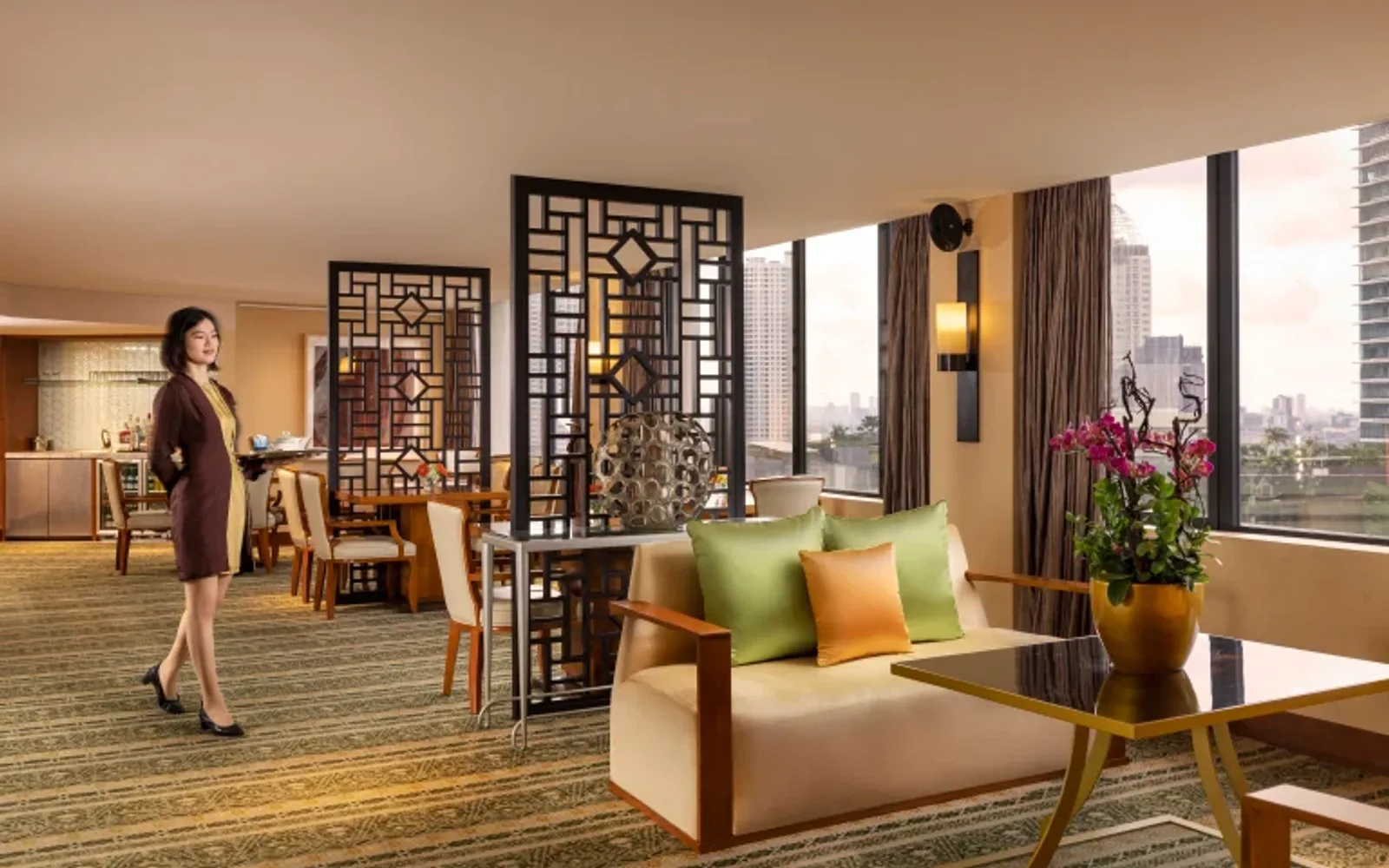 Waitress serving guests in the elegant Mandarin Oriental Club Lounge in Jakarta, featuring city views, Asian-inspired décor, and comfortable seating areas.