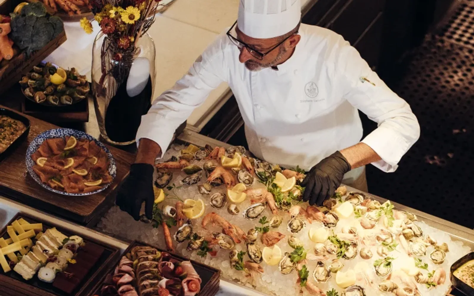 Chef in white uniform and hat prepares dishes at a buffet table with assorted food items at Mandarin Oriental Lutetia, Paris