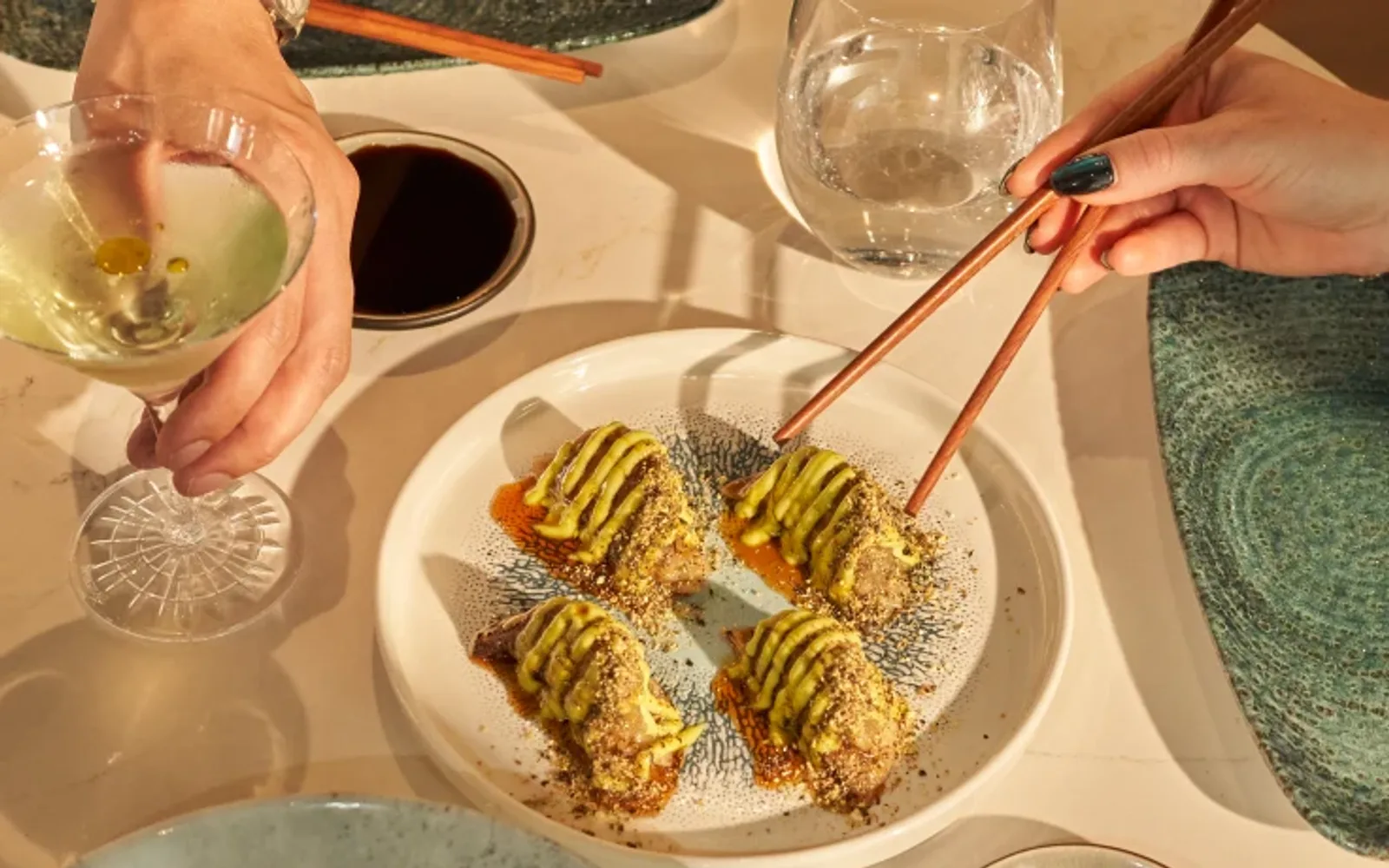 Close-up of Matsuri dishes, featuring a hand using chopsticks to interact with the food at Mandarin Oriental, Santiago