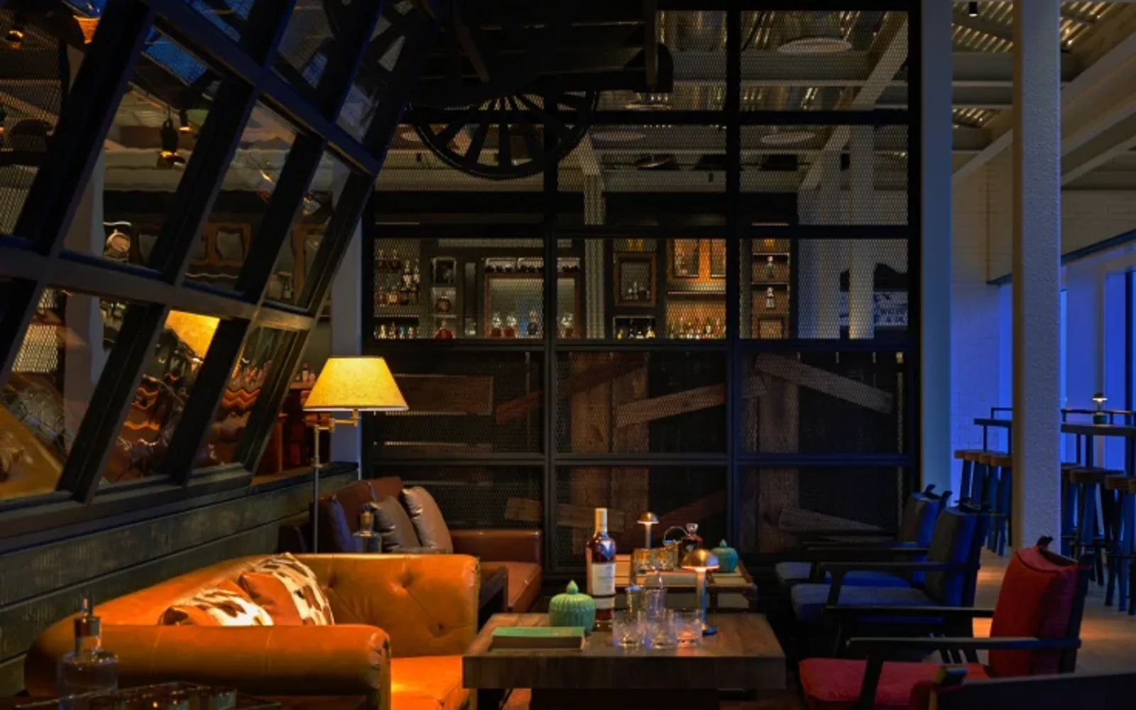 Industrial-style rooftop bar with skyline views, leather seating, wooden tables, and warm ambient lighting.