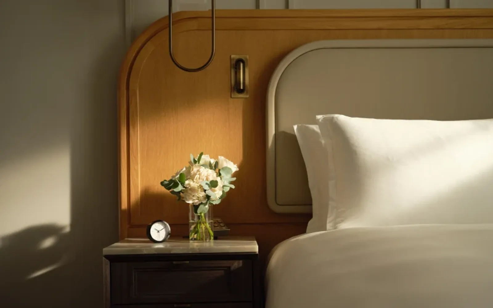 Side table next to a bed in a luxury hotel suite.