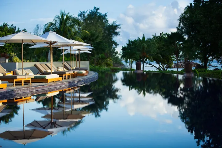 Swimming pool and shaded sun loungers at Raffles Seychelles