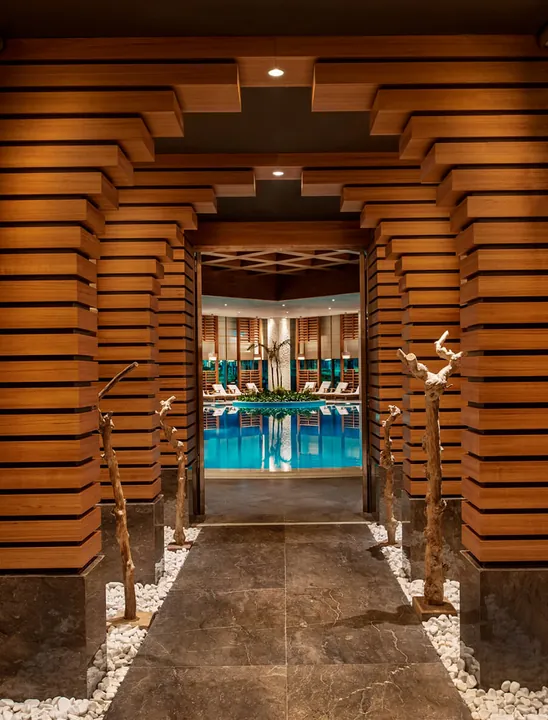 Wood-lined passage leading towards the indoor pool at GreenDoor Spa, Regnum Carya