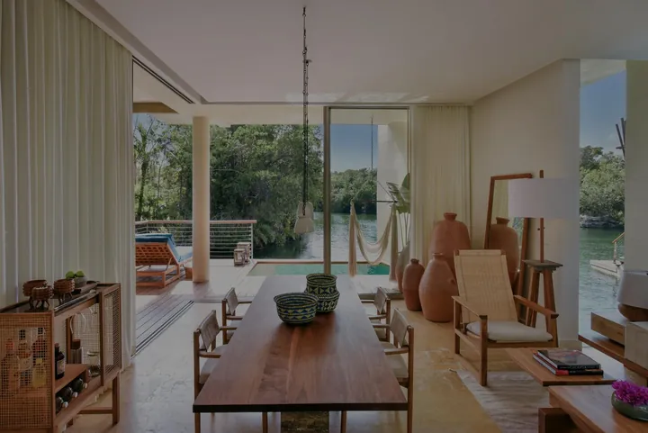 Living and dining area opening towards the lagoon in a Deluxe Overwater Lagoon Suite at Rosewood Mayakoba