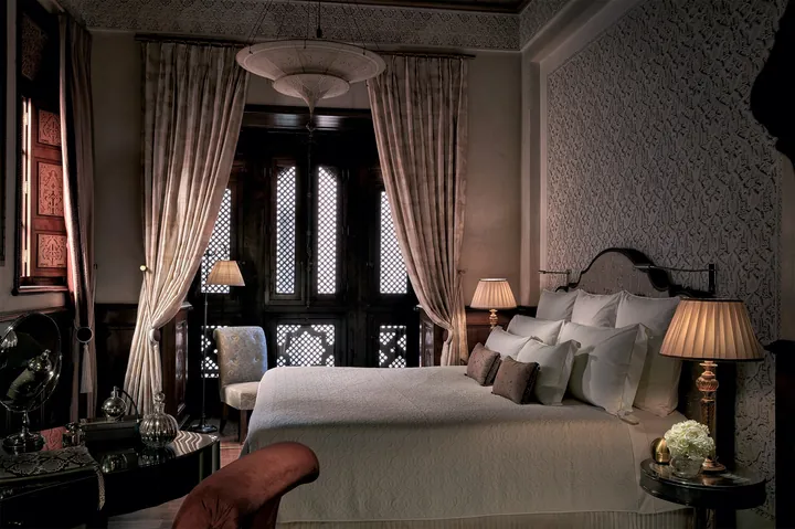Riad bedroom with a sitting area and patterned walls at Royal Mansour Marrakech
