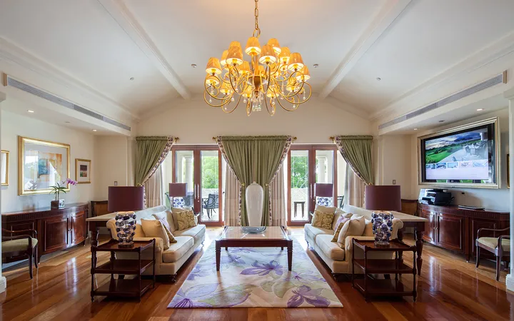 Suite living room with a chandelier and garden views at Sandy Lane, Barbados