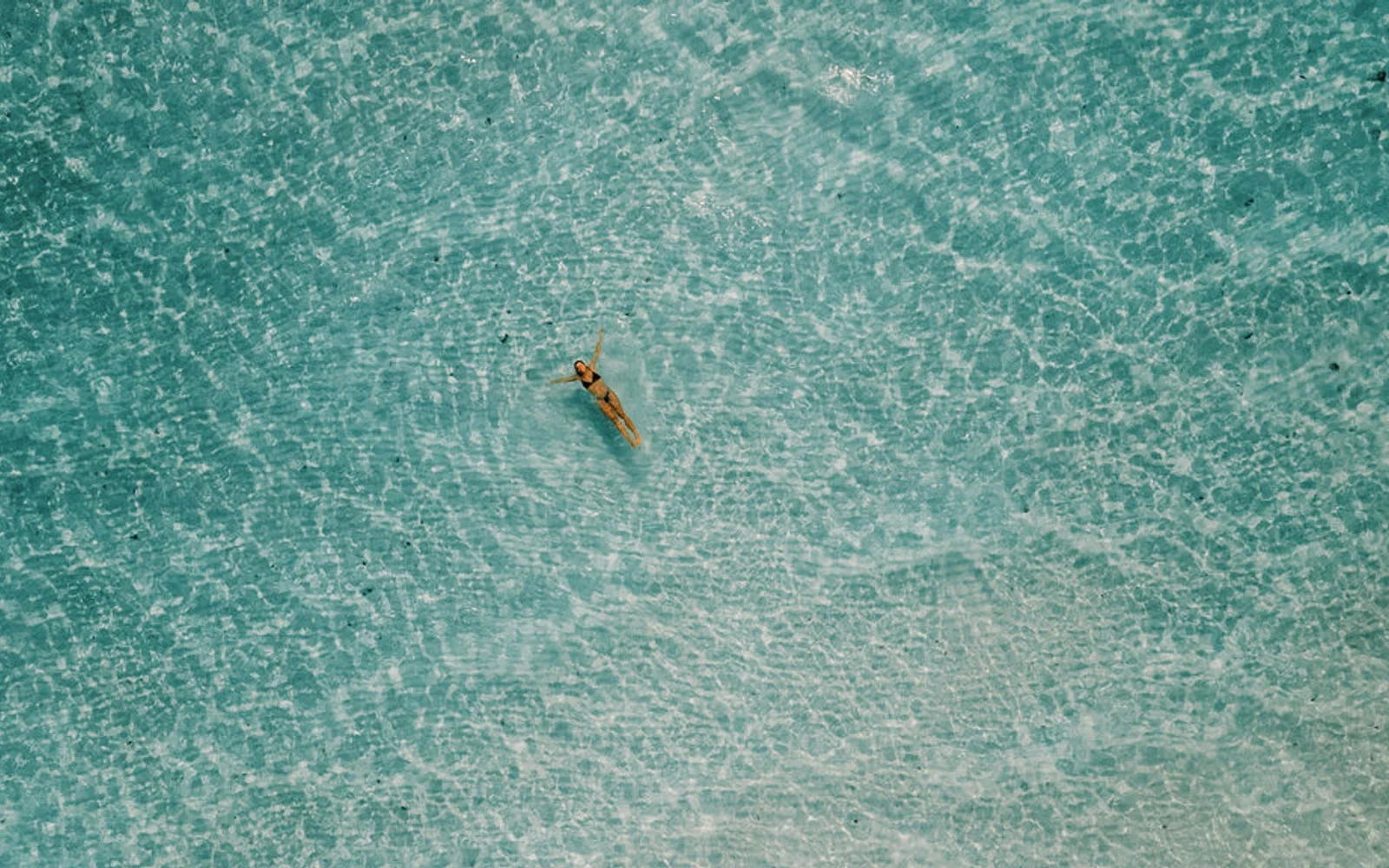 Guest floating in the clear lagoon at Soneva Jani